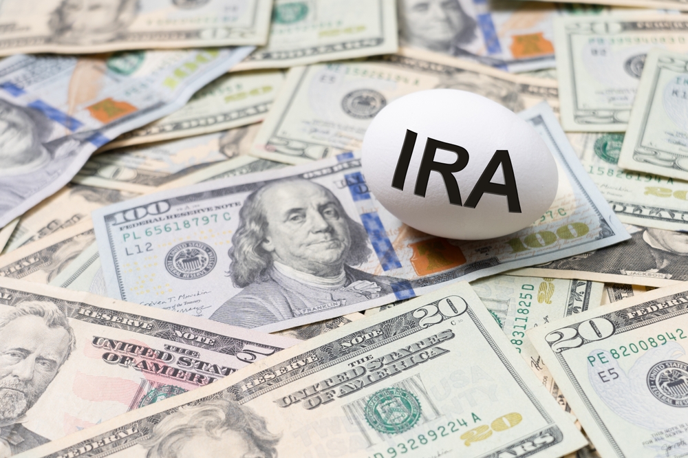 Egg labeled “IRA” on U.S. dollar bills symbolizing Roth IRA retirement savings and investment accounts